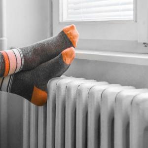 Eine Person trägt Socken, während sie sich an einem Heizkörper wärmt